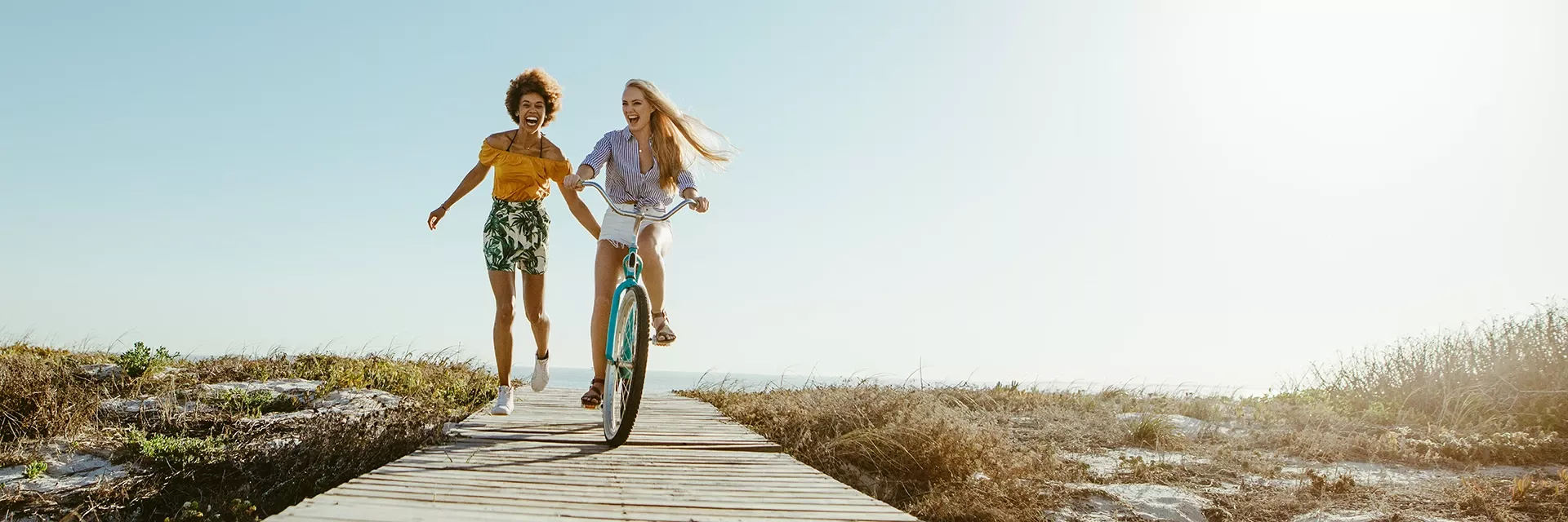 happy friends on a bike at the beach after weight loss procedure with dr jay suggs